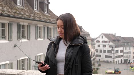 Young-attractive-woman-standing-in-front-of-city-of-Rapperswil,-Switzerland