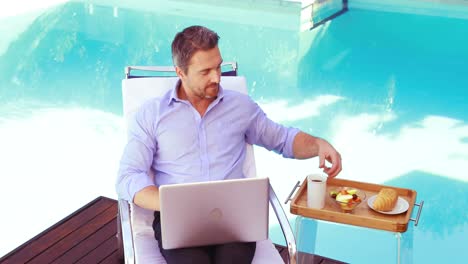 handsome man using laptop on deck chair