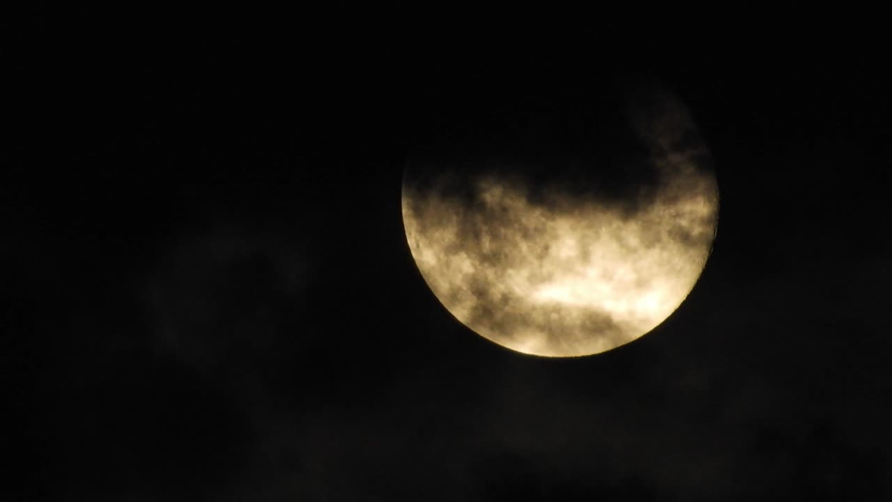 Moon at night with cloud real time. 4k video moon in the black sky.  Clouds passing by moon at night. night sky with cloudy weather
