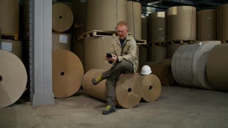 worker using smartphone in paper warehouse