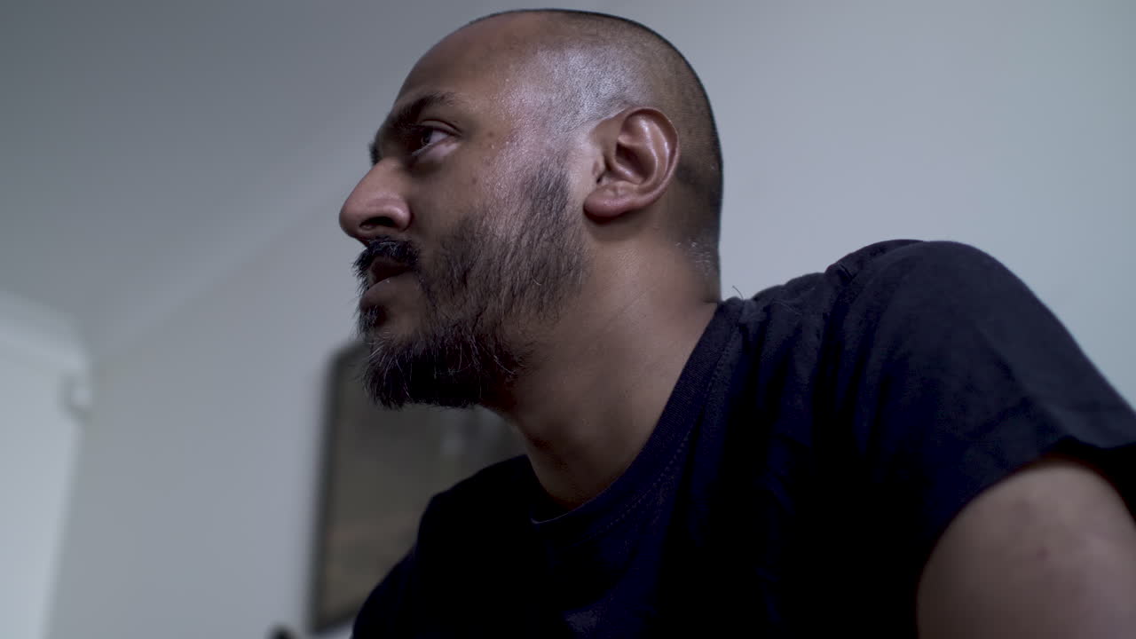 Bald UK Asian Male Watching TV Off Screen Expressively With Eyes