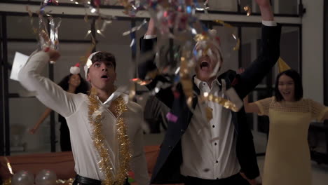 jóvenes hombres y mujeres emocionados bailando con confetti y celebrando una fiesta en casa