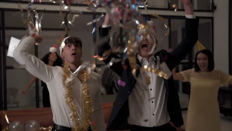 young excited men and women dancing with confetti and celebrating a party at home