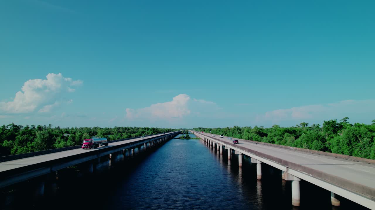 Aerial of red tanker truck crossing twin bridge over bayou in Louisiana