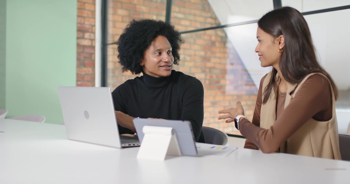 African American team in office man speaking typing laptop right woman gesturing at tablet planning
