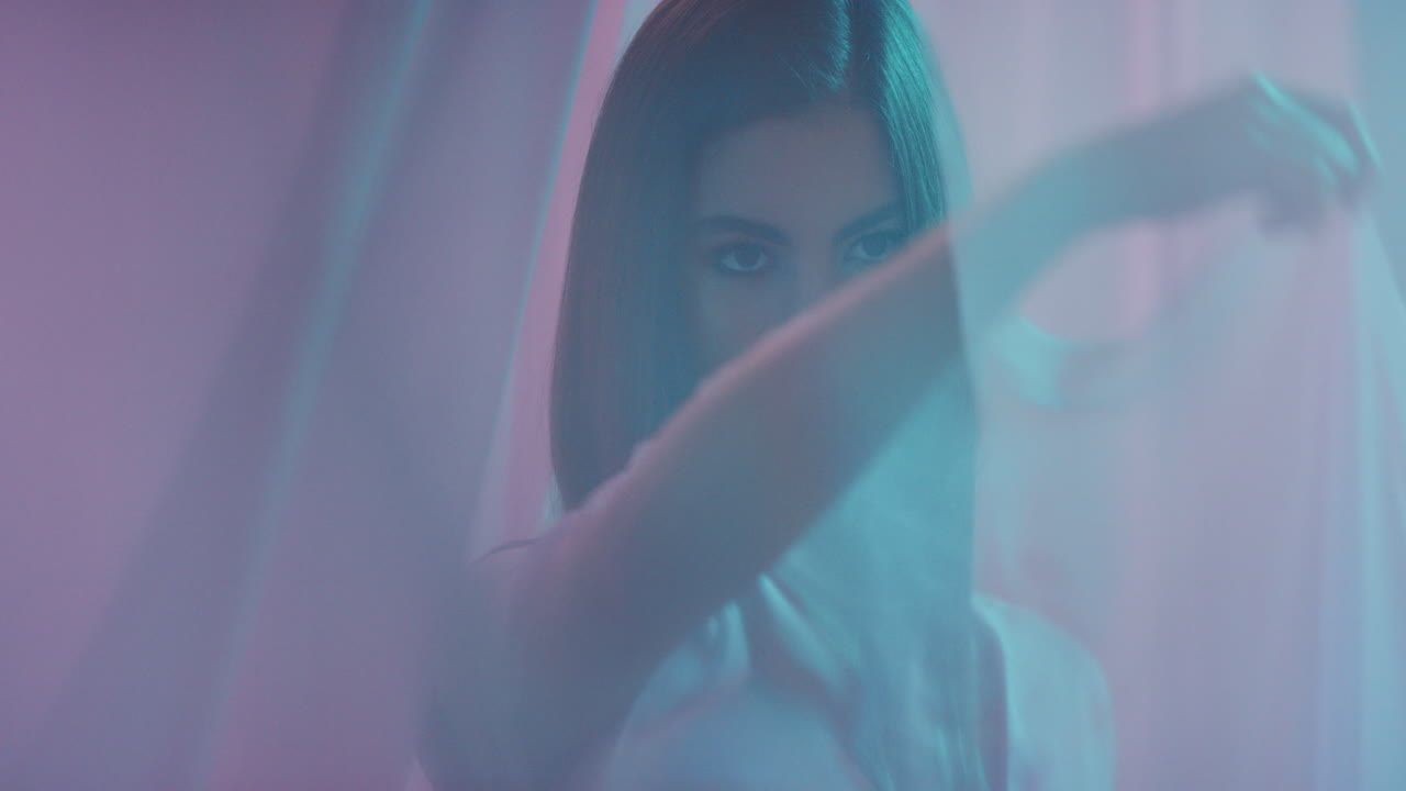 다채로운 판타지 아름다운 젊은 여성이 커튼 사이에 춤을 추고 우아한 감각적인 여성은 다채로운 배경에서 장난스러운 아름다움을 즐기고 있습니다.