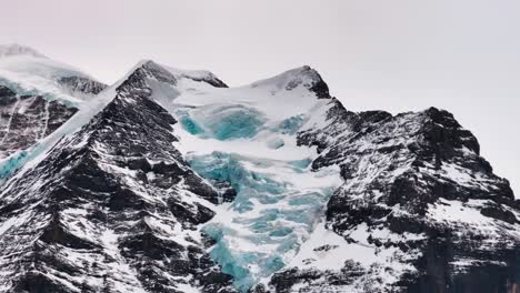 close up of dark rugged switzerland mountain with snow covered glacier on side