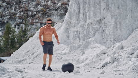 sport man exercising on nature. fitness guy doing workout with medicine ball on nature