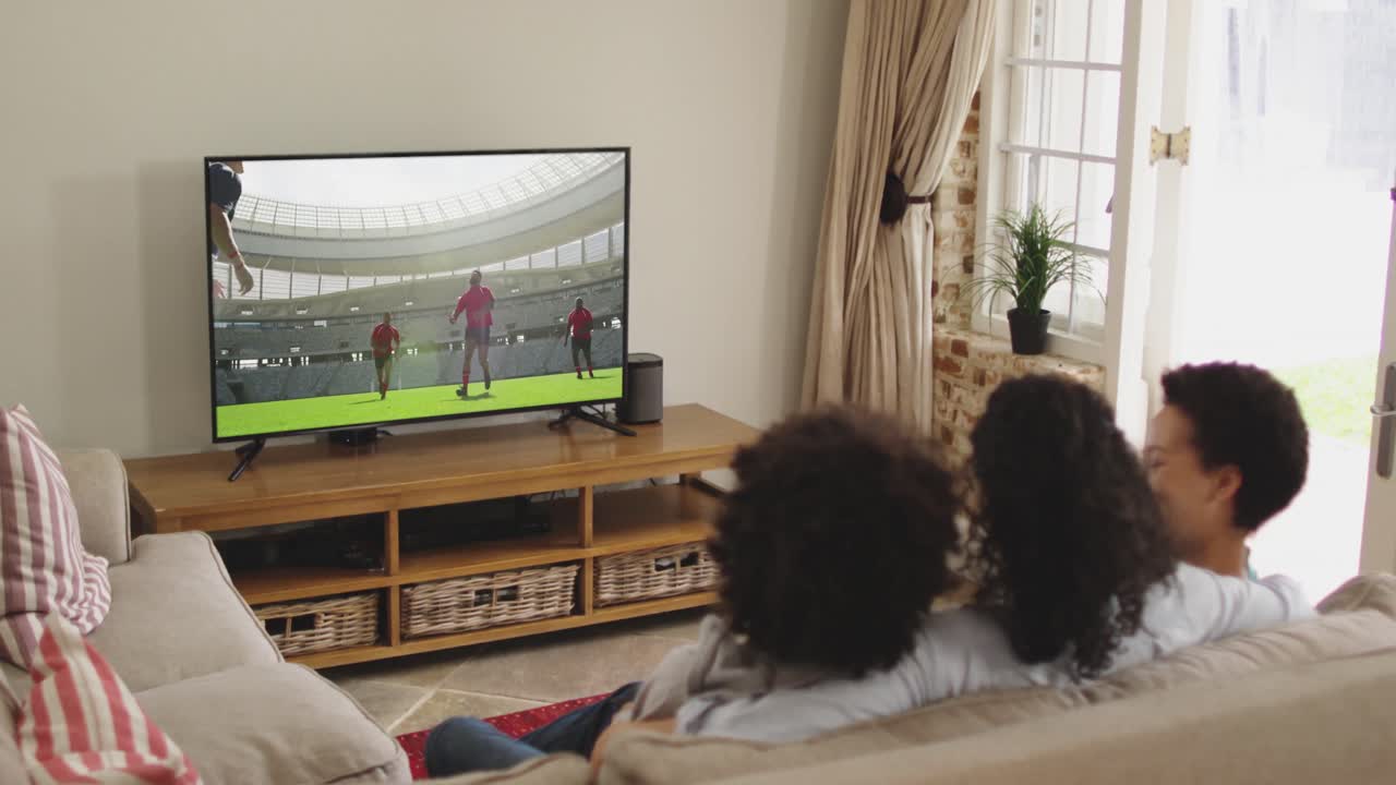 Famiglia felice seduta a casa insieme che guarda una partita di rugby in TV