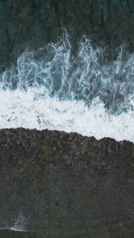 drone descends on whitewash waves breaking on shallow fringing reef in ocean water