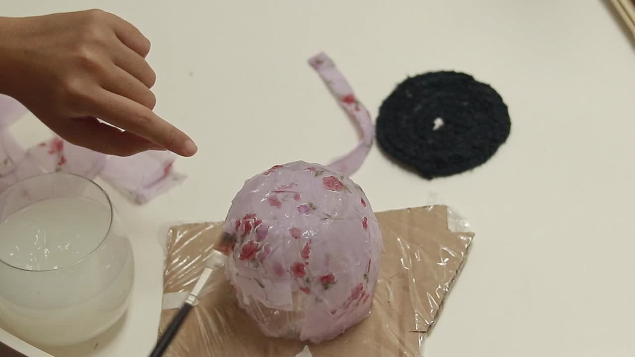 Layering recycled strips of fabric and cornstarch glue on a mold to create a pencil holder, DIY craft project