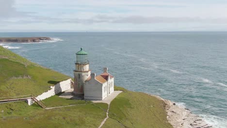 historic lighthouse on cliff side, aerial push in shot