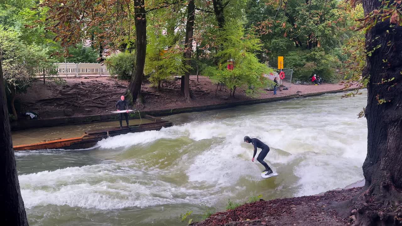 Efterår Surfere Flodsurfing morgen Eisbachwelle Eisbach Isar Flod München Tyskland Englischer Garten kunstig stående bølge turist ser på attraktion action sport stunts drejning slash