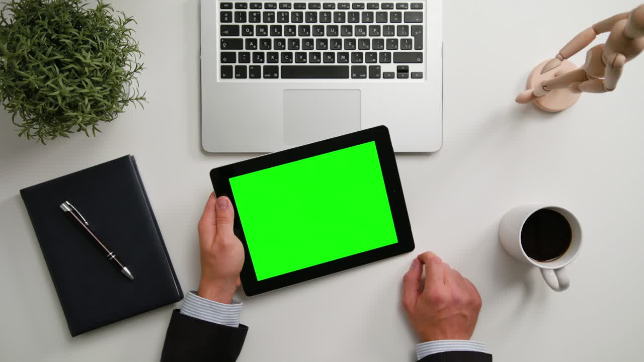 руки человека, держащего цифровой планшет с зеленым экраном