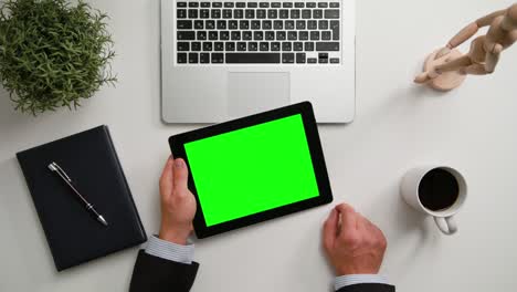 las manos de un hombre sosteniendo una tableta digital con una pantalla verde