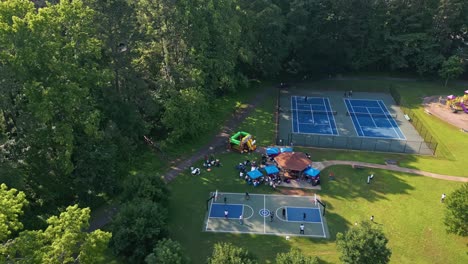 people playing basketball and tennis near the playground. - aerial shot