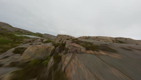 fpv-drohnen-näheflug über kanten von klippen und einem kleinen see in ramsvik, schweden