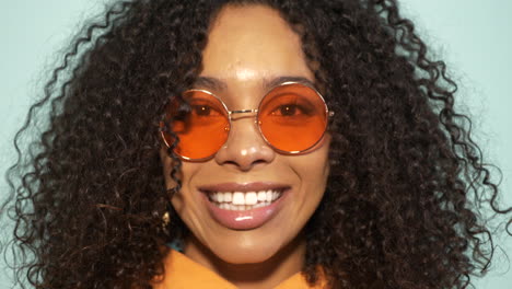 smiling woman with curly hair and orange sunglasses