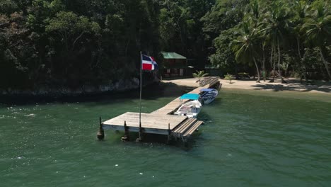 Flagge-Der-Dominikanischen-Republik-Auf-Einem-Kleinen-Holzsteg-Am-Strand-Und-Unter-Palmen
