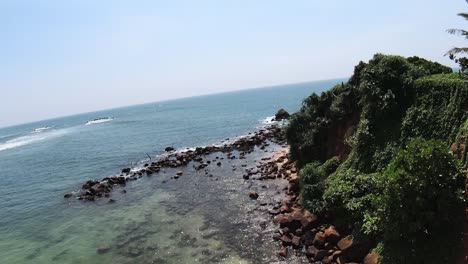 Areal-Low-Shot-Of-Rocky-Small-Island-Surrounded-By-Blue-Ocean-At-Mirissa-Beach,-Sri-Lanka