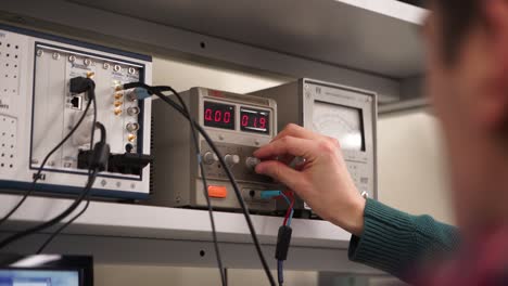estudiante ajustando el suministro de energía en un laboratorio