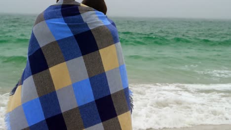 Rear-view-of-Caucasian-couple-in-blanket-standing-on-the-beach-4k
