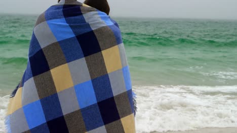 rear view of caucasian couple in blanket standing on the beach 4k