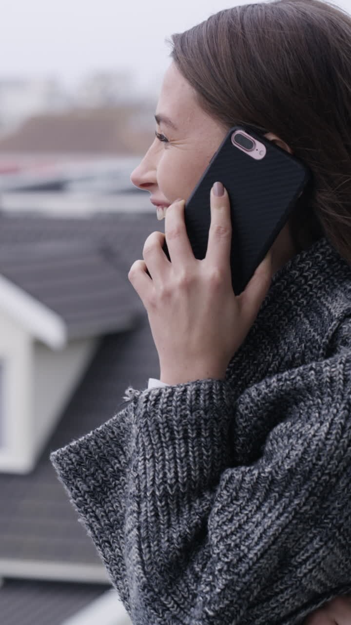 Giovane donna che ride mentre parla al telefono all'aperto