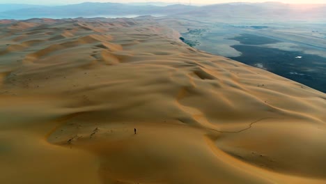 aerial view of a man walking alone in the top of dunes, u.a.e.