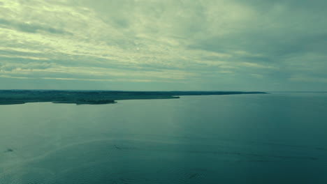 A-calm-green-blue-sea,-several-clouds-in-the-sky-and-gentle-waves-on-the-water