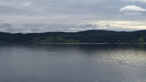 View-of-mountains-from-the-stern-of-a-ship-cruising-along-Saguenay-Fjord-outside-of-La-Baie,-QC,-Canada