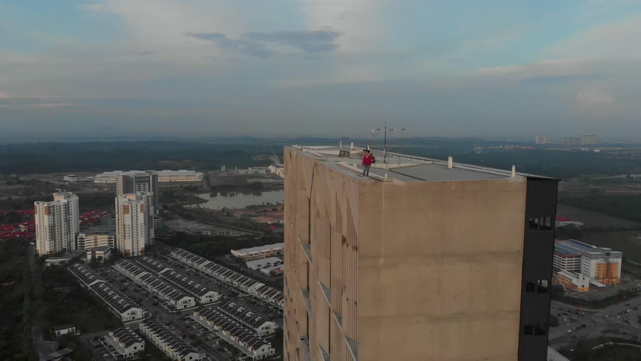 Pemandangan udara wanita di atap dengan kompleks apartemen bersinar saat matahari terbit di Cyberjaya Malaysia