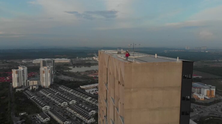 Vista aerea di una donna sul tetto con un complesso residenziale che risplende all'alba a Cyberjaya, Malesia.