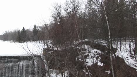 Die-Kamera-Schwenkt-Von-Einer-Ländlichen-Winterlandschaft-Nach-Links-Zum-Damm-Neben-Einer-Mühle-Mit-Wasserrad