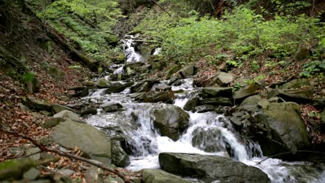 Mountain-waterfall-in-rocky-path-among-green-forest.-Flowing-water-in-nature