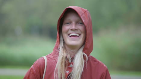 young cheerful blonde girl smiling in red hoodie with blurred nature on the background in netherlands