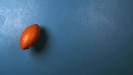 american football ball rotating on blue background with copyspace