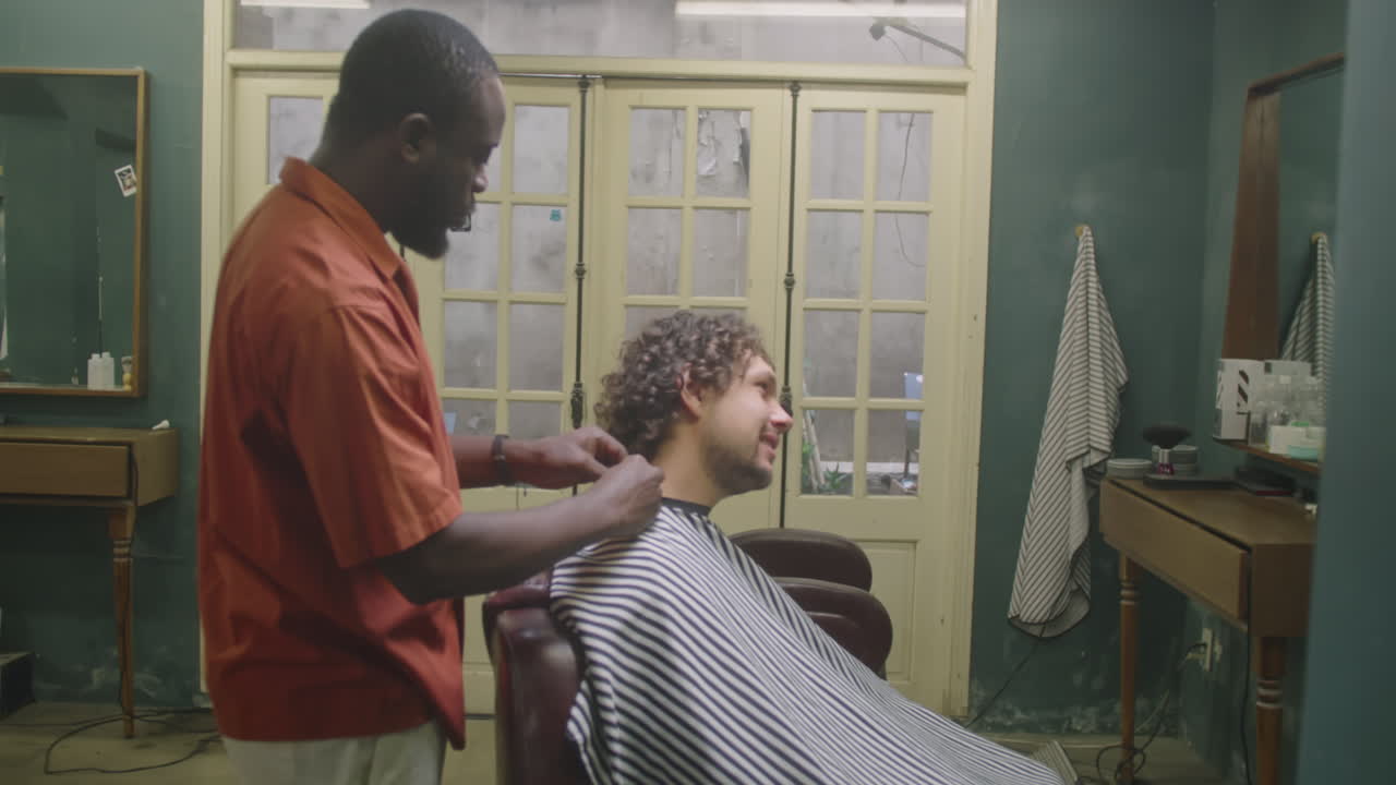 Barber Greeting Client And Putting Hairdressing Cape on Him