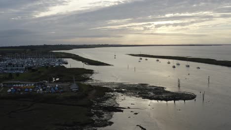 Beautiful-yellow-sunset-with-a-cooling-feeling-over-moored-boats-in-Essex,-UK