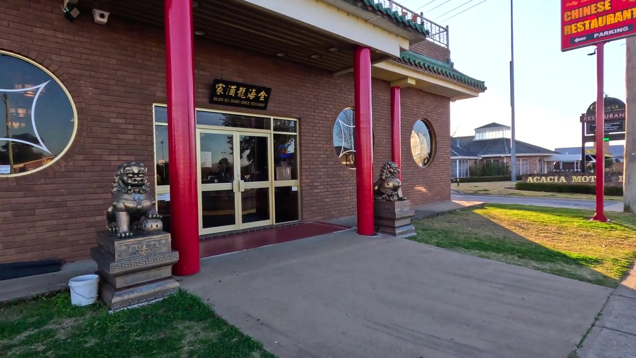 広角カメラが郊外の通りをパンし、伝統的なレンガ造りの中国料理店の方へ向かう