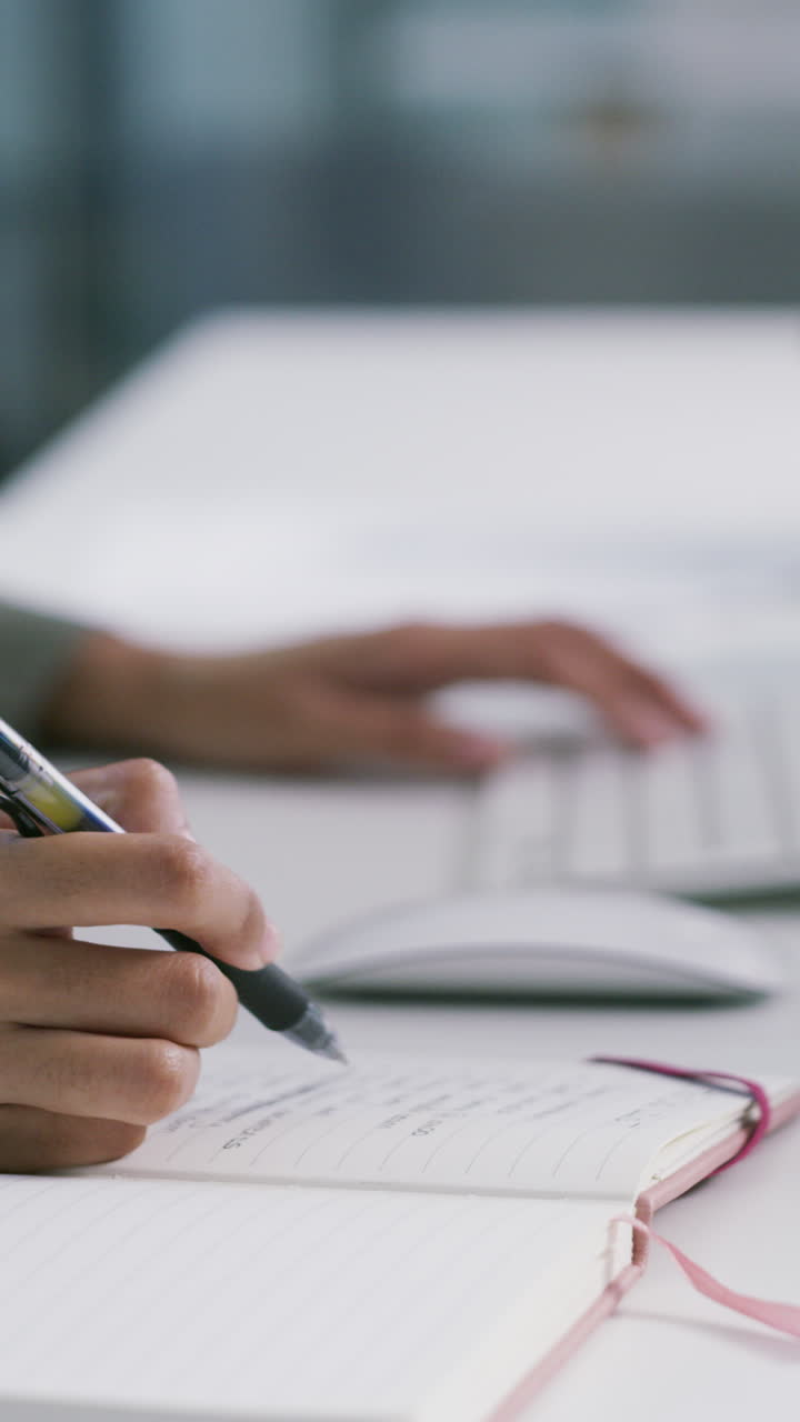 Primo piano di mani che digitano sulla tastiera e scrivono su un quaderno.