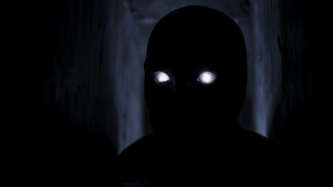 Figura erguida con traje oscuro inclinándose y cambiando ojos blancos en un pasillo oscuro, la puerta retroiluminada causa un resplandor