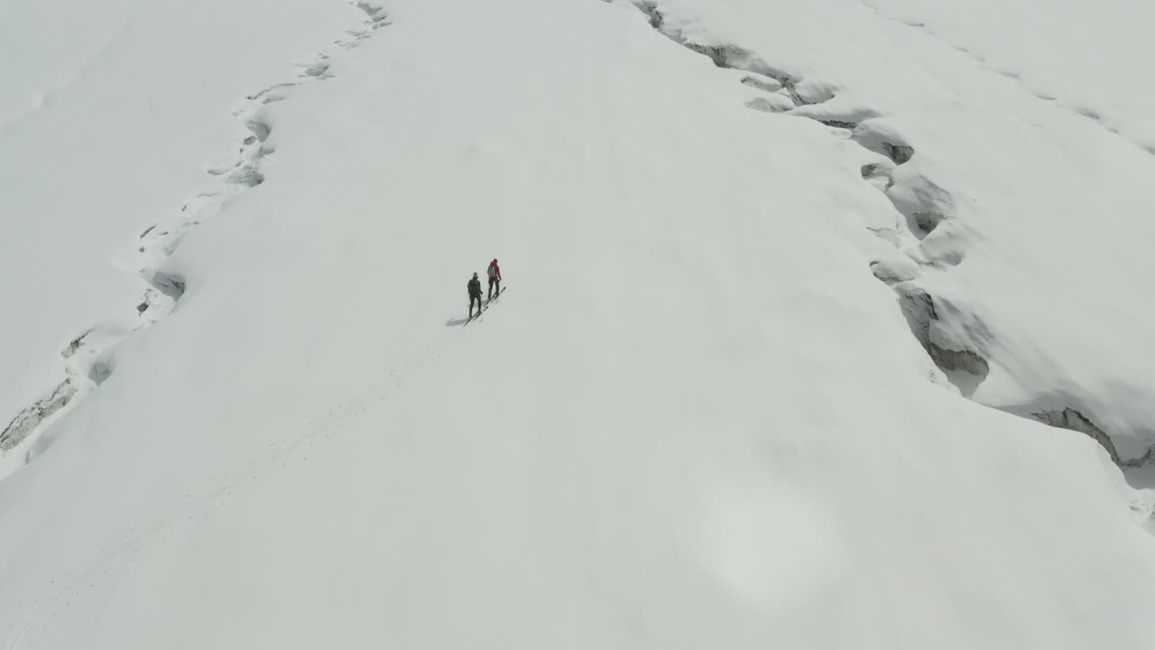 Snow-covered Kyrgyzstan landscape with two hikers trekking across the frozen terrain
