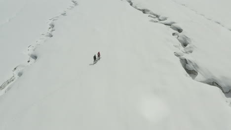 snow-covered kyrgyzstan landscape with two hikers trekking across the frozen terrain