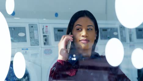 Woman-talking-on-mobile-phone-at-laundromat-4k