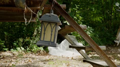 Lantern-swings-from-back-of-old-rusty-caravan-camping-trailer-outdoor-scene