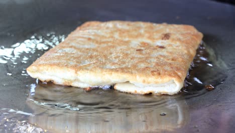 Street-food-vendor-is-pan-frying-Murtabak,-a-spicy-omelette-pancake-filled-with-bits-of-vegetables-and-minced-meat