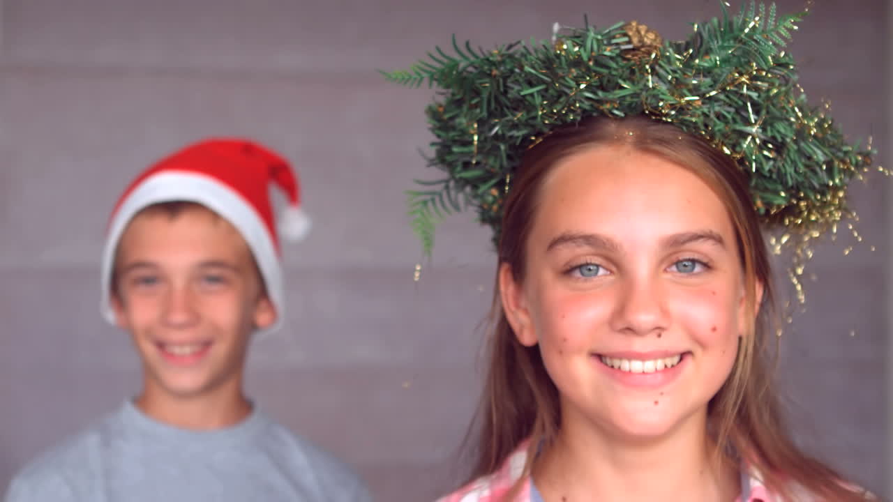 Siblings wearing garland and hat to celebrate christmas