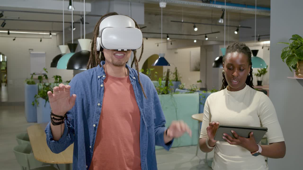 Squadra afroamericana testa la VR in ufficio dopo l'avvio del visore, uomo gesticola, donna tocca il tablet