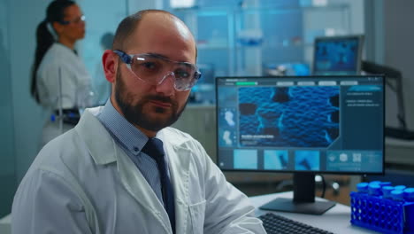 overworked scientist with protection glasses looking at camera sighing